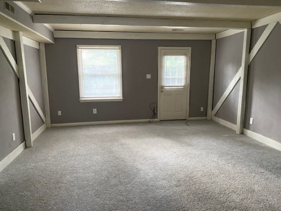 an empty room with a door and two windows