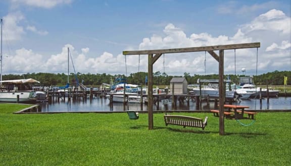 a park with a bench and swing next to a marina