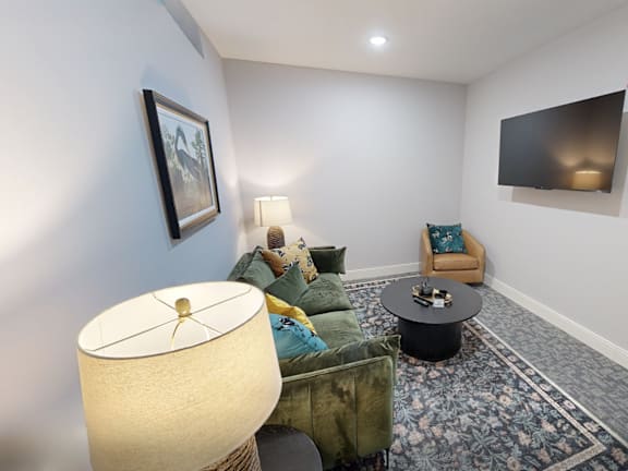 A living room with a sofa, a table, a lamp and a painting on the wall.