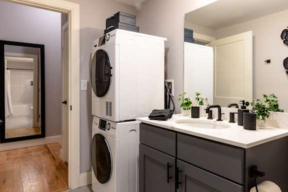 A white washing machine and dryer stacked on top of each other in a laundry room.
