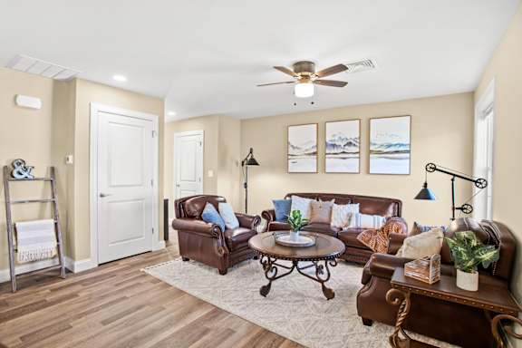 A living room with a brown leather couch and a white door.