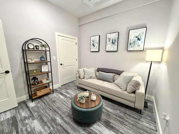 A living room with a grey couch, a wooden coffee table, and a black bookshelf.