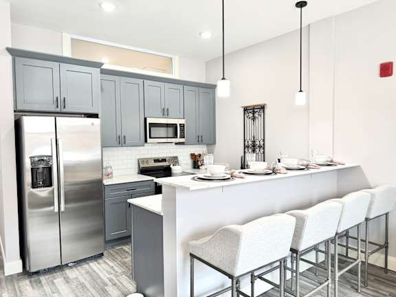 A modern kitchen with a white island and grey cabinets.