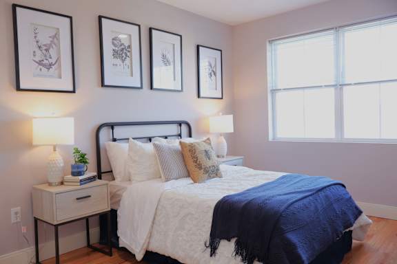 A bedroom with a bed, nightstand, and three framed pictures on the wall.