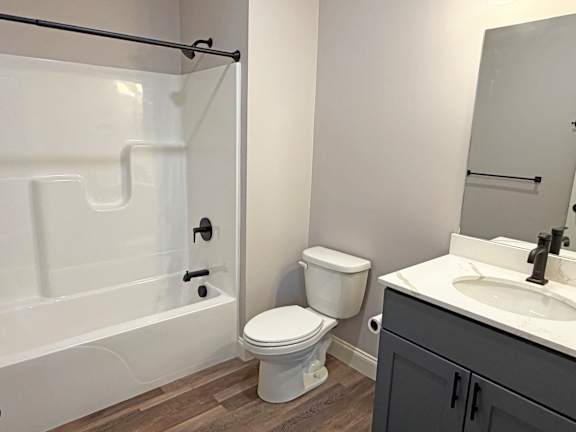 A white toilet sits next to a white bathtub in a bathroom.