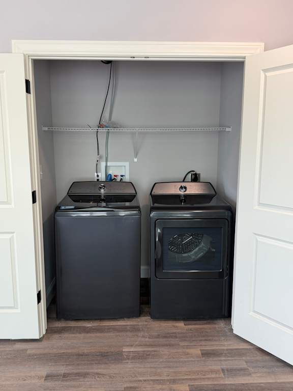 A microwave is sitting on top of a refrigerator inside of a kitchen cabinet.