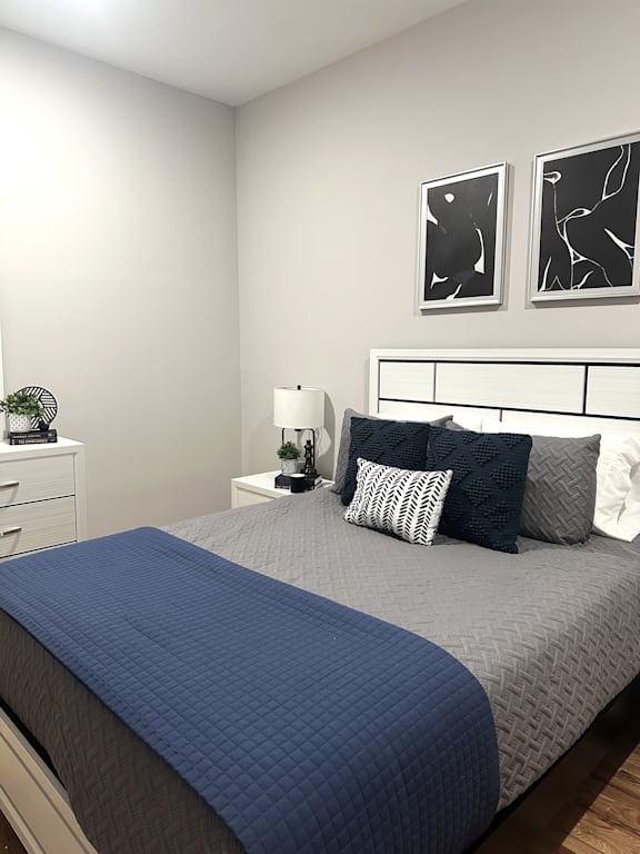 A bed with a blue comforter and pillows in a white room.
