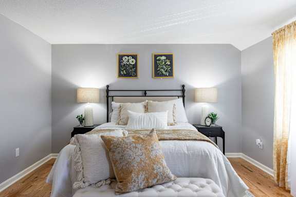 A bedroom with a large bed and two lamps on either side of the bed.