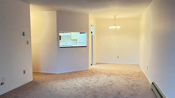 A room with a carpet floor and a chandelier hanging from the ceiling.