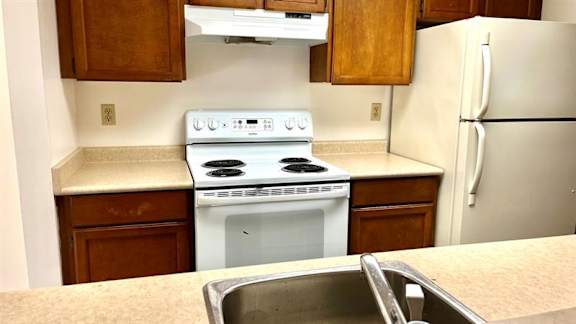 A white stove and oven in a kitchen with wooden cabinets.