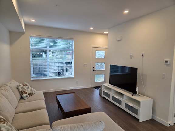 A living room with a couch, a coffee table, and a television.