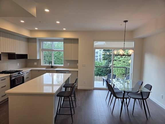 A kitchen with a white counter top and black chairs.