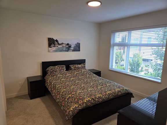 A bedroom with a bed, nightstand, and window.