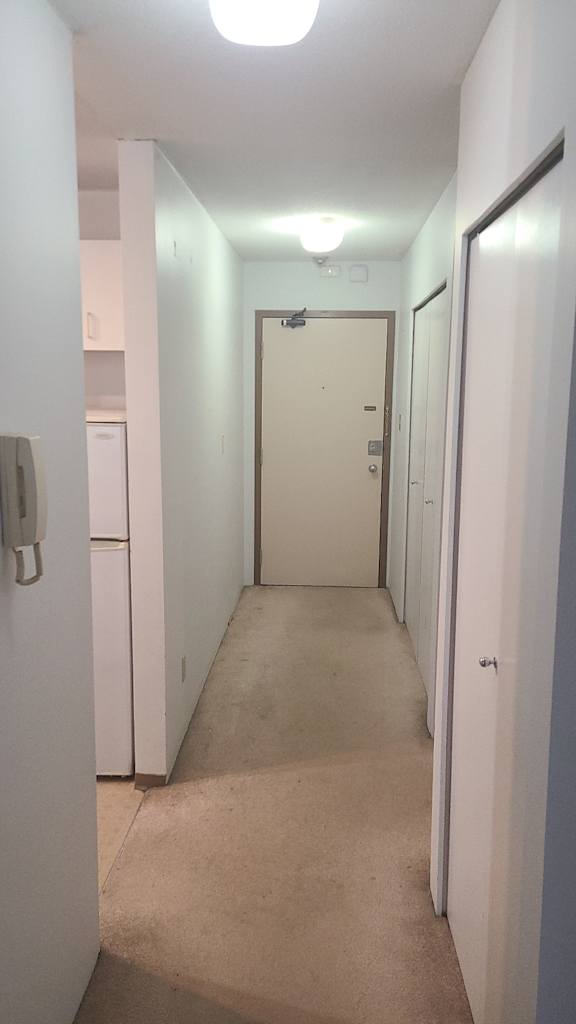 a hallway with white walls and a white door at the end of the hallway