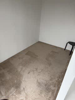 A room with a dirty carpet and a black chair.