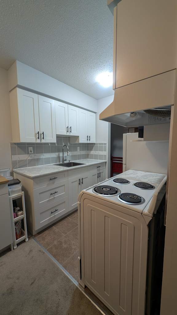 A kitchen with a stove top oven and cabinets.