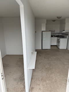 A kitchen with white appliances and a white wall.