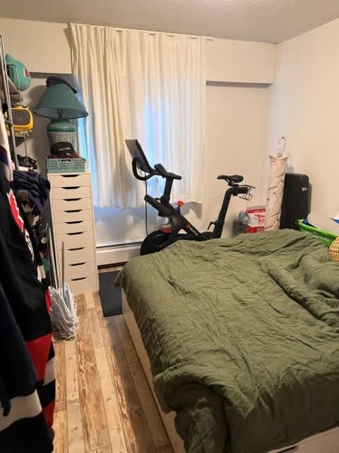 A bedroom with a bed, a chair, and a bicycle.
