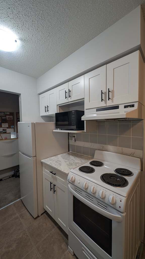 A kitchen with a stove, refrigerator, and cabinets.