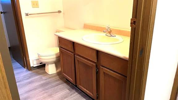 A bathroom with a toilet, sink and wooden cabinets.