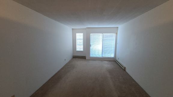 a bedroom with white walls and a large window
