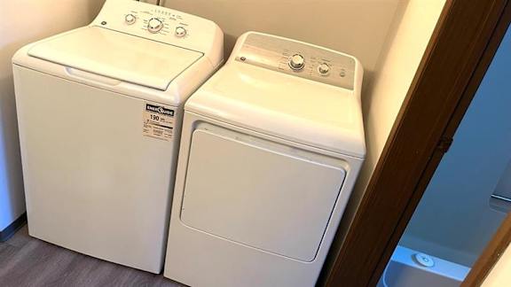 Two white front loading washing machines in a laundry room.