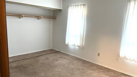 A room with a carpeted floor and a window with curtains.