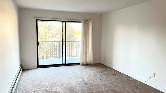 A room with a sliding glass door leading to a balcony.
