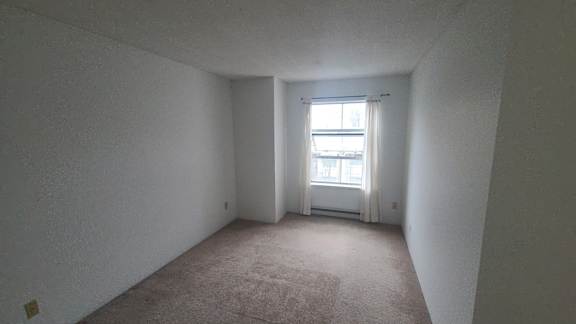 an empty room with a window and a carpet