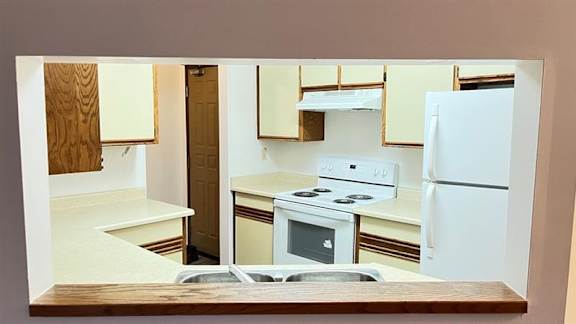 A kitchen with a white refrigerator, stove, and oven.