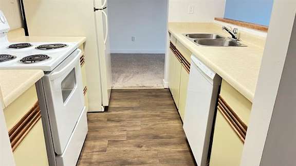 A kitchen with a stove, refrigerator, and sink.