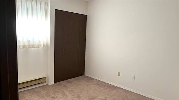 A room with a brown door and a window with white curtains.