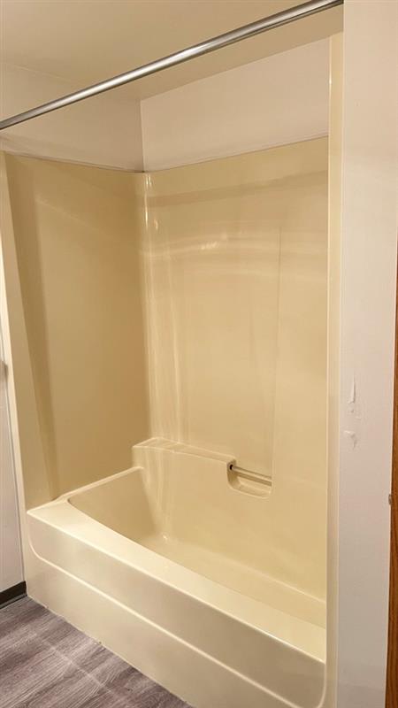 A white bathtub with a shower head attached to the wall.