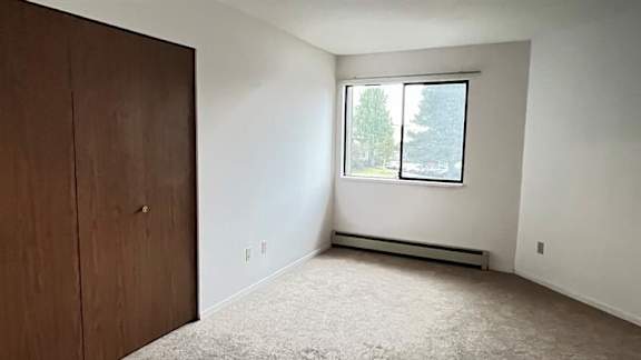 A room with a brown door and a window showing trees outside.
