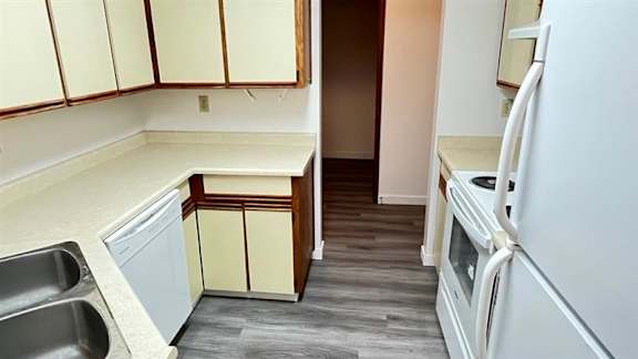 A kitchen with white appliances and wooden cabinets.