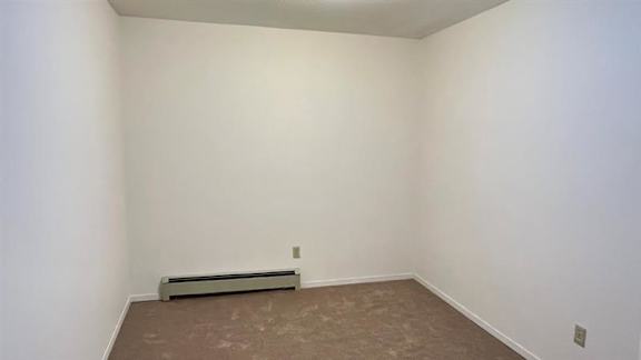 A room with a brown carpet and a wall-mounted air conditioner.