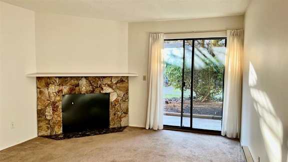 A room with a stone fireplace and sliding glass doors.