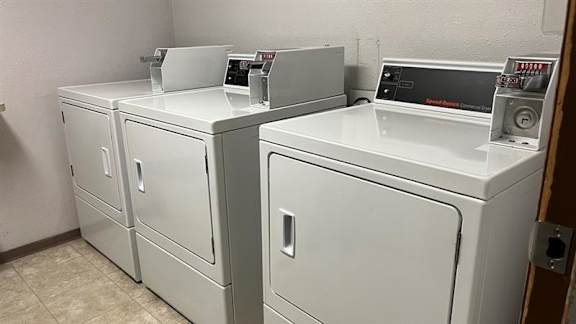 Two white washing machines in a laundry room.