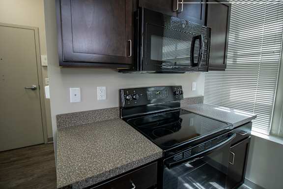 A black stove top oven with a black microwave above it.