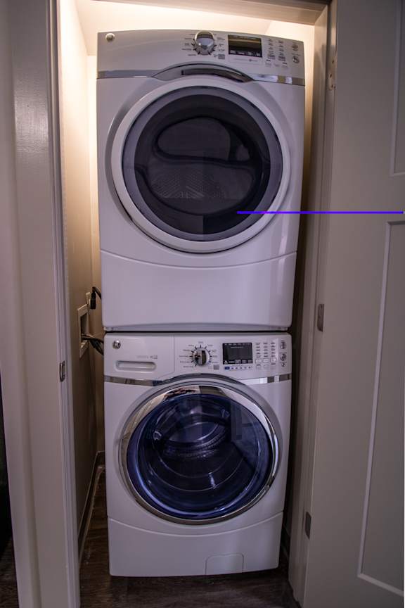 Two white front loading washing machines in a small laundry room.
