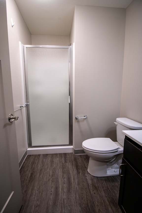A white toilet in a small bathroom with a walk-in shower.
