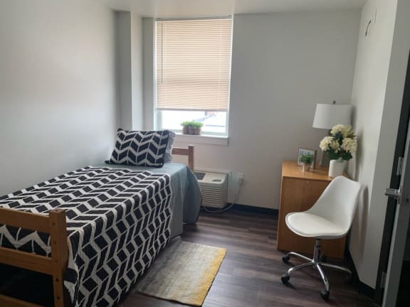 a bedroom with a bed and a desk and a window
