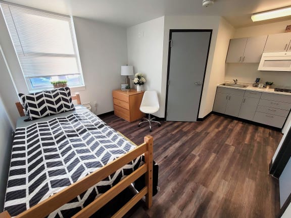 a small bedroom with a bed and a kitchen