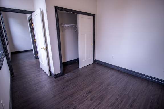 an empty living room with wood flooring and a closet
