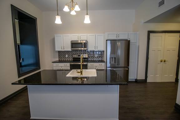 A modern kitchen with a black countertop and stainless steel appliances.