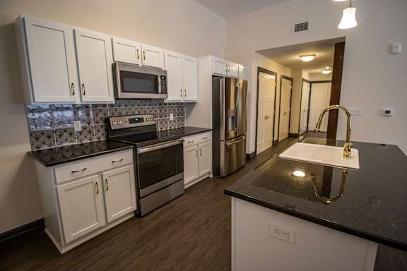 A kitchen with white cabinets and a black countertop.