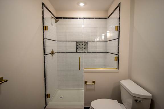 A white toilet sits next to a walk-in shower with a glass door.