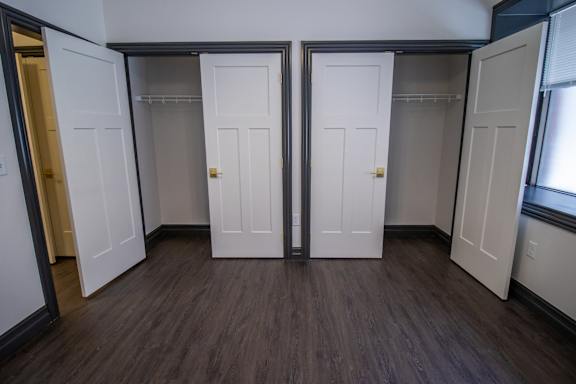 A room with four white doors and wood floors.