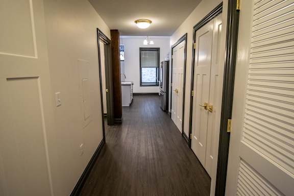 A long hallway with white walls and wood floors.