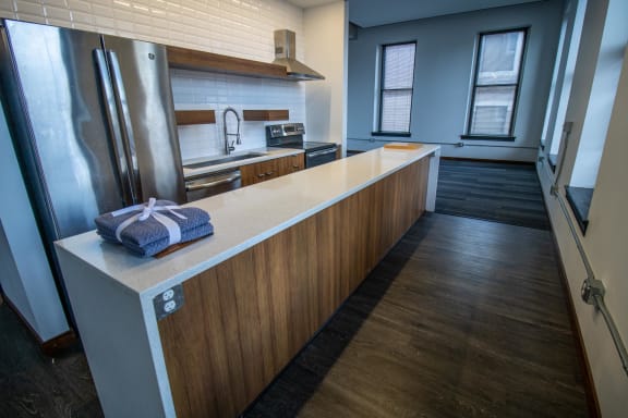 a kitchen with a long counter and a stainless steel refrigerator